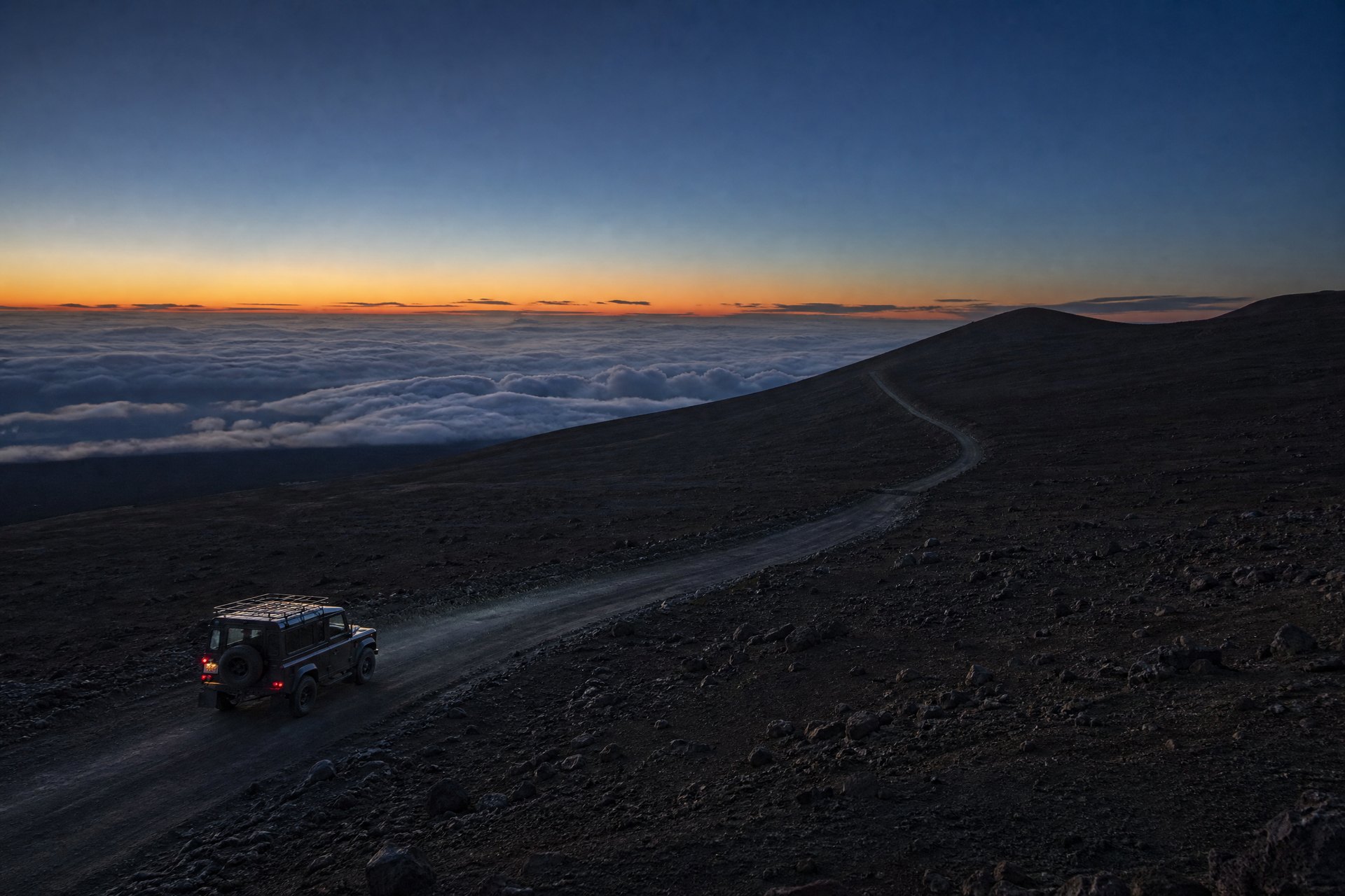 Unbranded four-wheel-drive vehicle traveling carefully on a Mauna Kea high-altitude access road